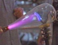 The purple light is produced by the electric discharge in the gas.